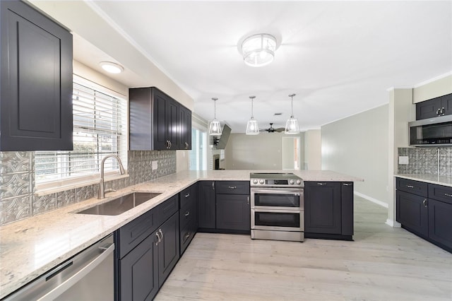 kitchen featuring kitchen peninsula, sink, backsplash, pendant lighting, and appliances with stainless steel finishes