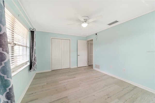 unfurnished bedroom with ornamental molding, light wood-type flooring, ceiling fan, and a closet