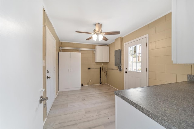 interior space with electric panel, cabinets, ornamental molding, ceiling fan, and light hardwood / wood-style flooring