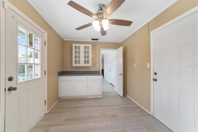 entryway with tile walls, light hardwood / wood-style floors, ornamental molding, and ceiling fan