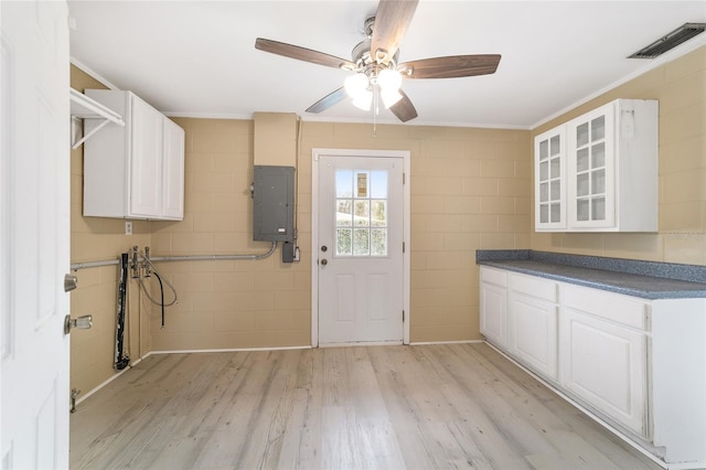 laundry room with electric panel, light wood-type flooring, tile walls, and ornamental molding