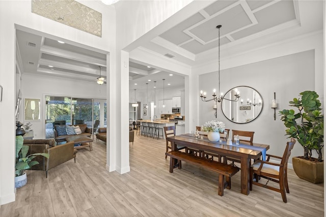 dining room with coffered ceiling, a high ceiling, light wood-type flooring, ceiling fan with notable chandelier, and ornamental molding