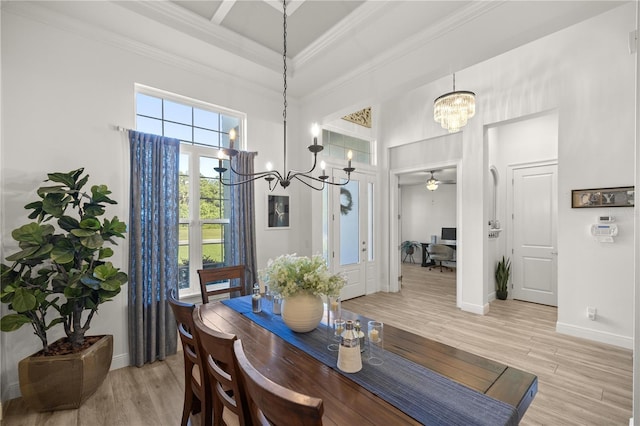 dining area featuring ceiling fan with notable chandelier, ornamental molding, a high ceiling, and light hardwood / wood-style flooring