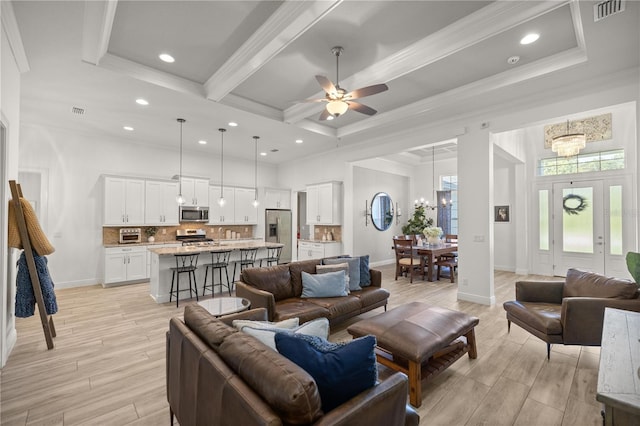 living room with ceiling fan with notable chandelier, light hardwood / wood-style flooring, and ornamental molding