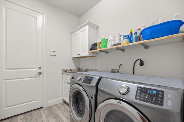 washroom featuring cabinets, light wood-type flooring, sink, and washing machine and clothes dryer