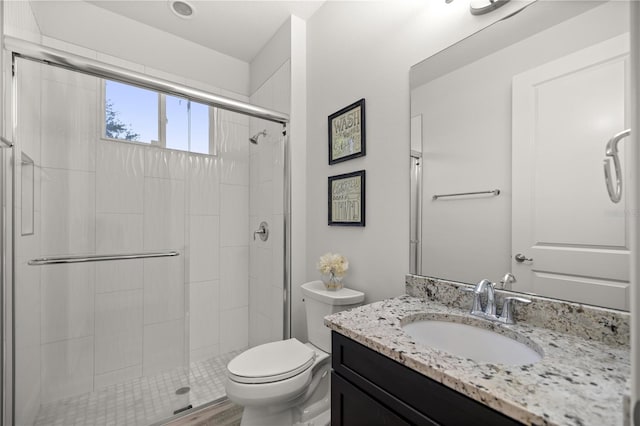 bathroom with an enclosed shower, vanity, and toilet