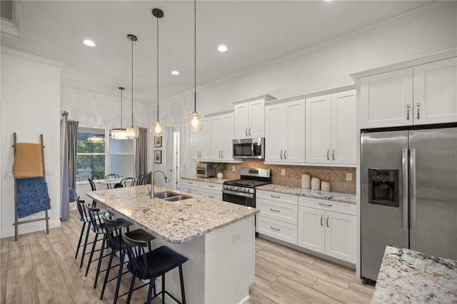 kitchen with pendant lighting, a center island with sink, light stone countertops, white cabinetry, and stainless steel appliances