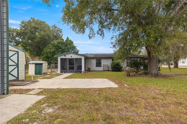 back of property featuring a storage shed, a sunroom, and a yard