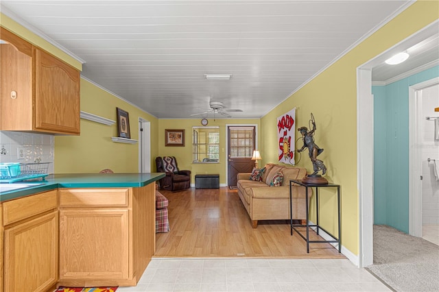 kitchen featuring light wood-type flooring, ceiling fan, crown molding, and backsplash