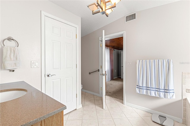 bathroom featuring sink, a textured ceiling, lofted ceiling, tile patterned floors, and toilet