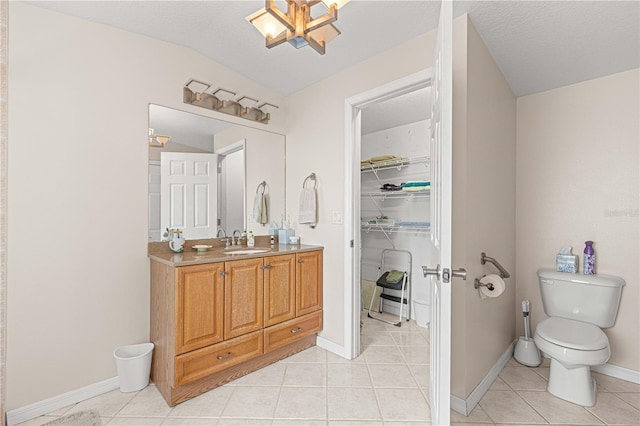 bathroom with lofted ceiling, toilet, tile patterned floors, a textured ceiling, and vanity