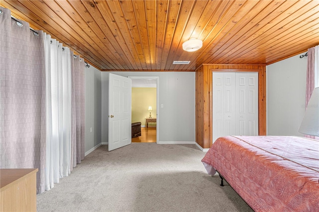 bedroom featuring a closet, wood ceiling, wooden walls, and carpet flooring