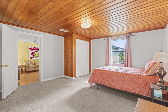 carpeted bedroom featuring wood walls, wood ceiling, and a closet