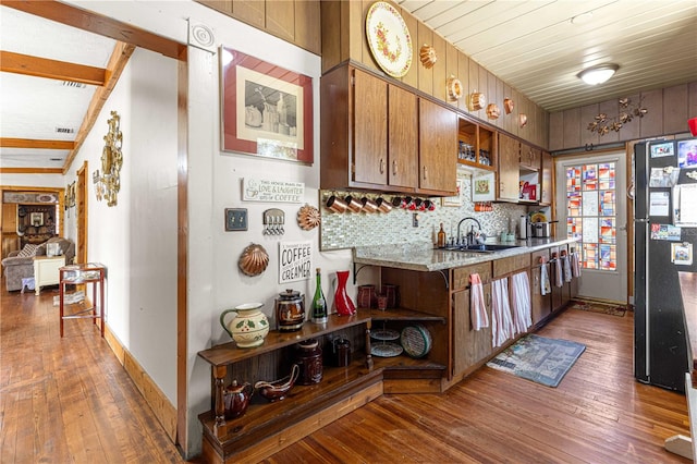 kitchen featuring dark wood-type flooring, vaulted ceiling, sink, backsplash, and stainless steel fridge