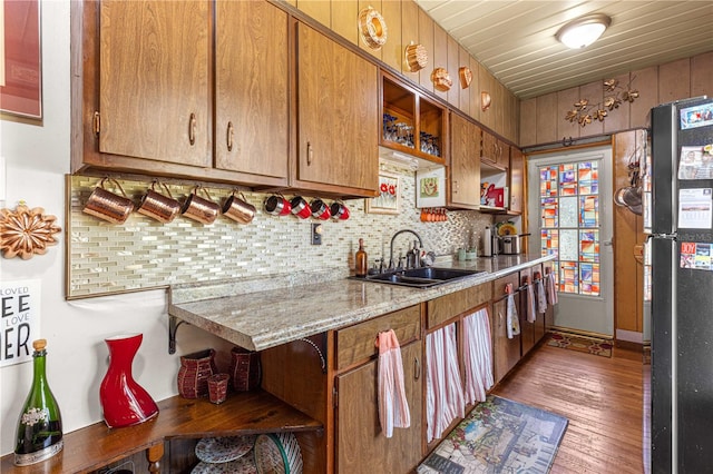 kitchen featuring sink, refrigerator, dark hardwood / wood-style floors, light stone countertops, and backsplash