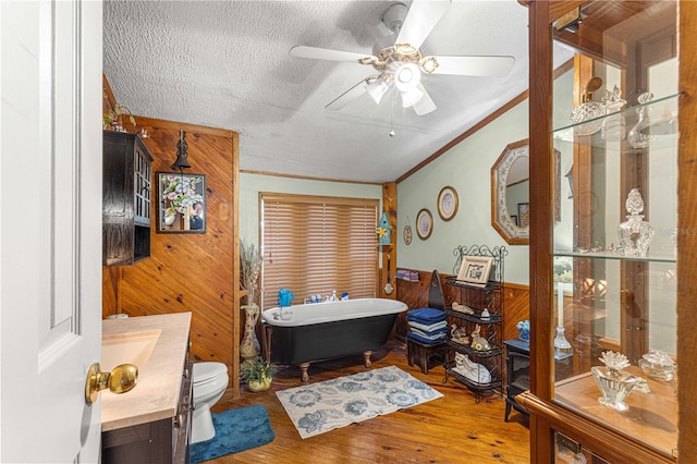 bathroom featuring vanity, a tub, a textured ceiling, wooden walls, and hardwood / wood-style flooring