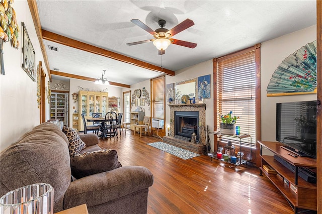 living room with ceiling fan, dark hardwood / wood-style floors, beam ceiling, and a textured ceiling