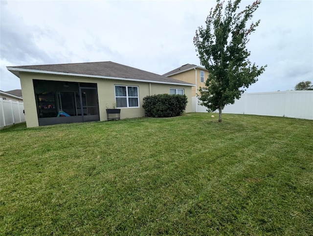 rear view of property with a sunroom and a yard