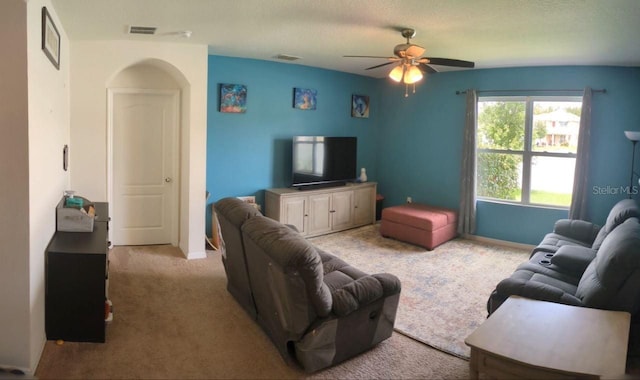 living room featuring a textured ceiling, light carpet, and ceiling fan