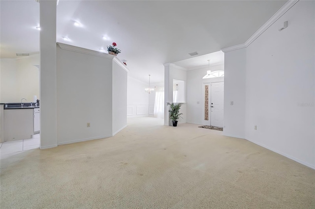 empty room featuring light colored carpet, a notable chandelier, sink, and crown molding