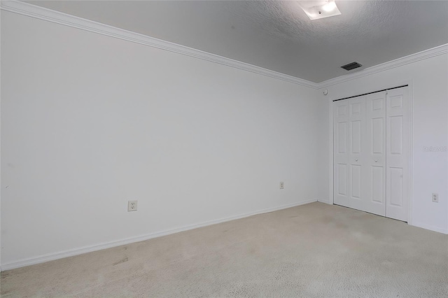 unfurnished bedroom with a textured ceiling, light carpet, a closet, and crown molding