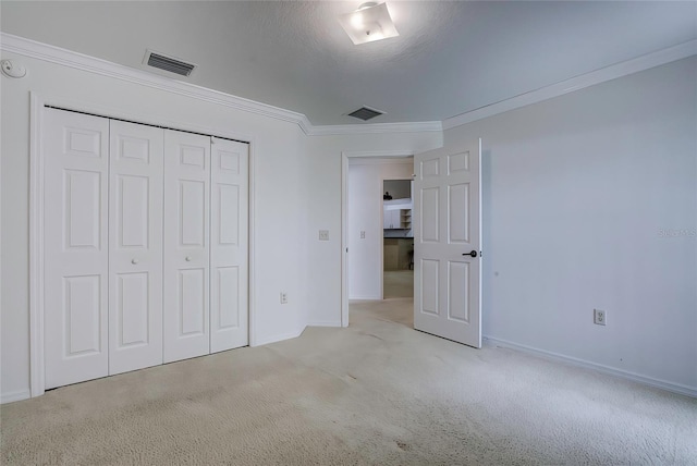 unfurnished bedroom featuring a closet, a textured ceiling, light carpet, and ornamental molding