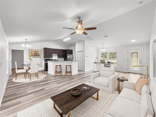 living room with lofted ceiling, light hardwood / wood-style floors, and ceiling fan with notable chandelier