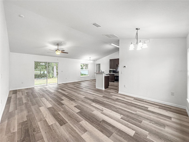 unfurnished living room with light wood-type flooring, ceiling fan with notable chandelier, and lofted ceiling