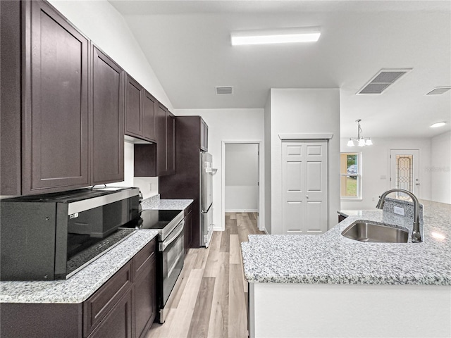 kitchen with an island with sink, sink, light wood-type flooring, and appliances with stainless steel finishes