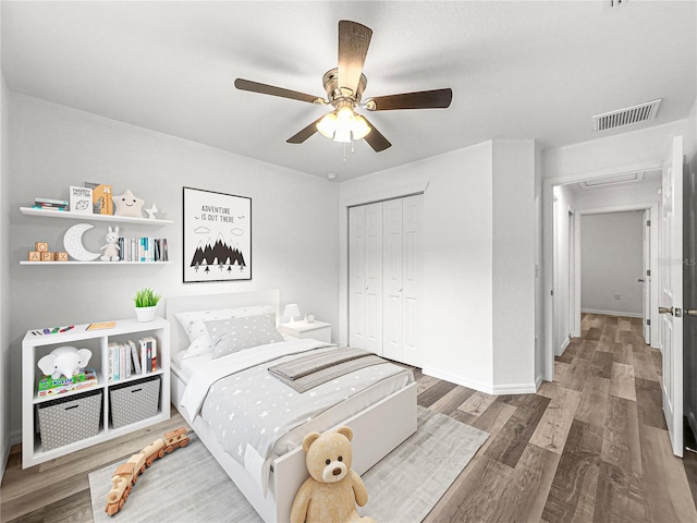 bedroom with dark wood-type flooring, ceiling fan, and a closet