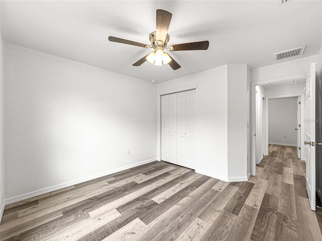 unfurnished bedroom featuring ceiling fan, dark hardwood / wood-style floors, and a closet