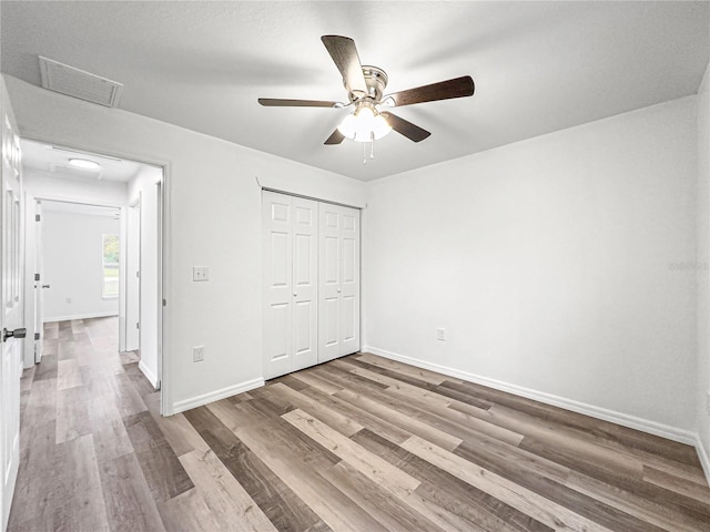 unfurnished bedroom with hardwood / wood-style flooring, ceiling fan, and a closet