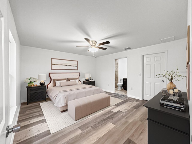 bedroom with hardwood / wood-style floors, ensuite bathroom, and ceiling fan