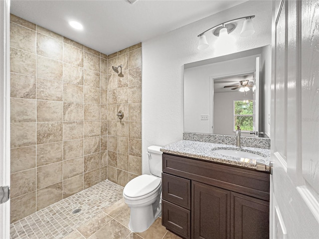 bathroom featuring tiled shower, vanity, ceiling fan, and toilet