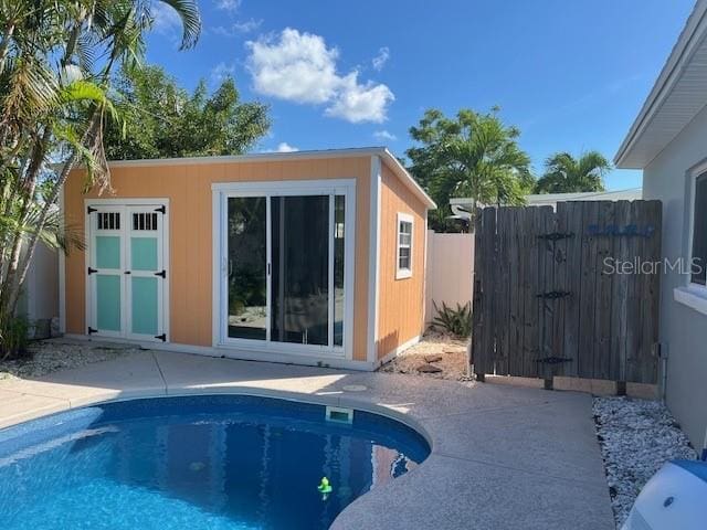 rear view of house featuring a shed, a patio, and a fenced in pool