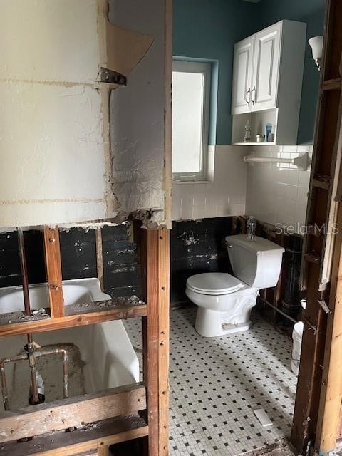 bathroom featuring toilet and tile walls