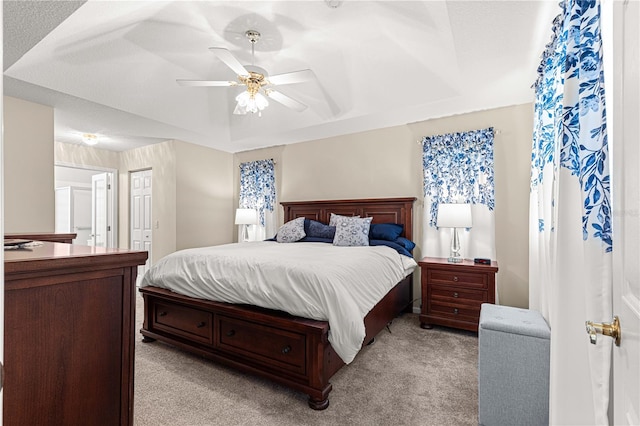 carpeted bedroom featuring a textured ceiling, ceiling fan, and a raised ceiling