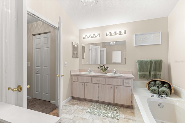 bathroom featuring vanity, a textured ceiling, and tiled tub