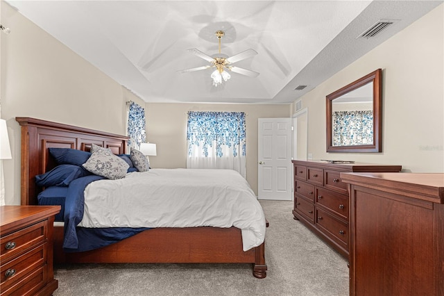 carpeted bedroom with ceiling fan and a tray ceiling