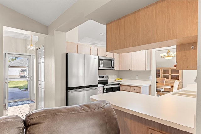 kitchen with stainless steel appliances, kitchen peninsula, light brown cabinets, decorative light fixtures, and lofted ceiling