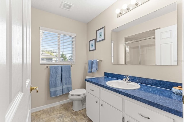 bathroom with a shower with shower door, vanity, toilet, and a textured ceiling