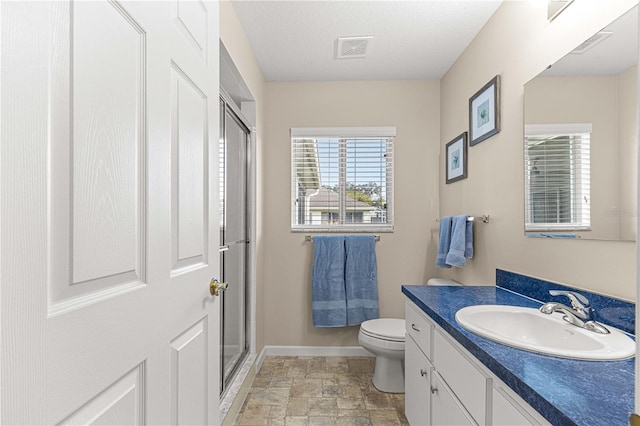 bathroom with vanity, toilet, an enclosed shower, and a textured ceiling