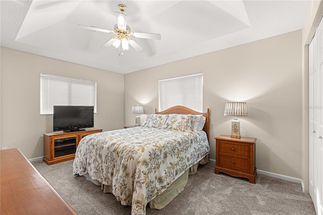 carpeted bedroom featuring ceiling fan, a closet, and a tray ceiling