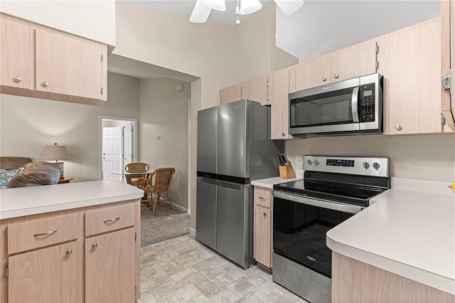 kitchen featuring light brown cabinetry, ceiling fan, a towering ceiling, and appliances with stainless steel finishes