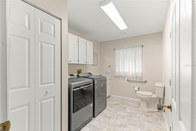 clothes washing area featuring cabinets and washer and dryer