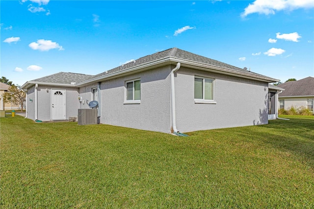 rear view of property with central air condition unit and a yard