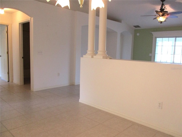 unfurnished room featuring ornate columns, ceiling fan, and light tile patterned flooring