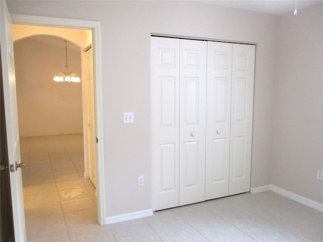 unfurnished bedroom with a chandelier, light tile patterned floors, and a closet