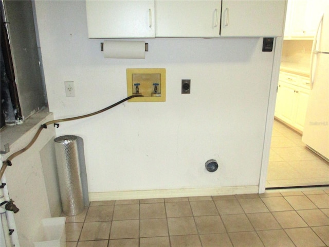 clothes washing area with hookup for an electric dryer, hookup for a washing machine, cabinets, and light tile patterned floors