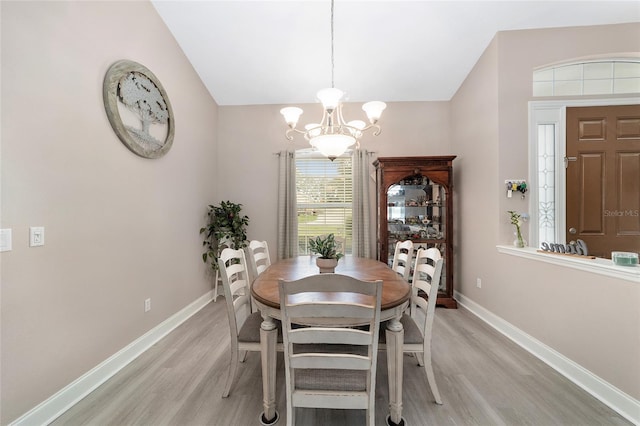 dining area with a chandelier, vaulted ceiling, and light hardwood / wood-style floors